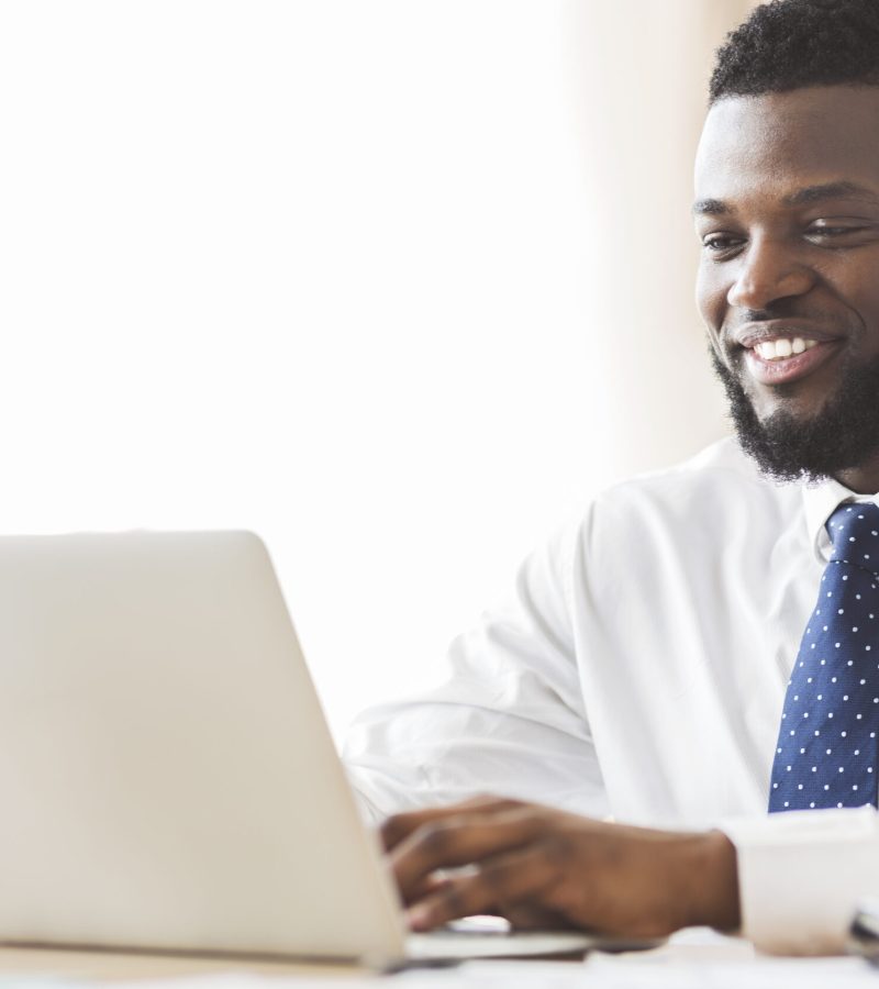 Young afro business consultant with headset typing email to client on laptop, empty space